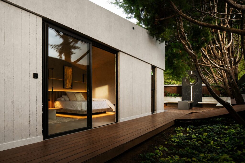 A Nebulae Module by day — clean concrete form with a private wood deck open to the gardens