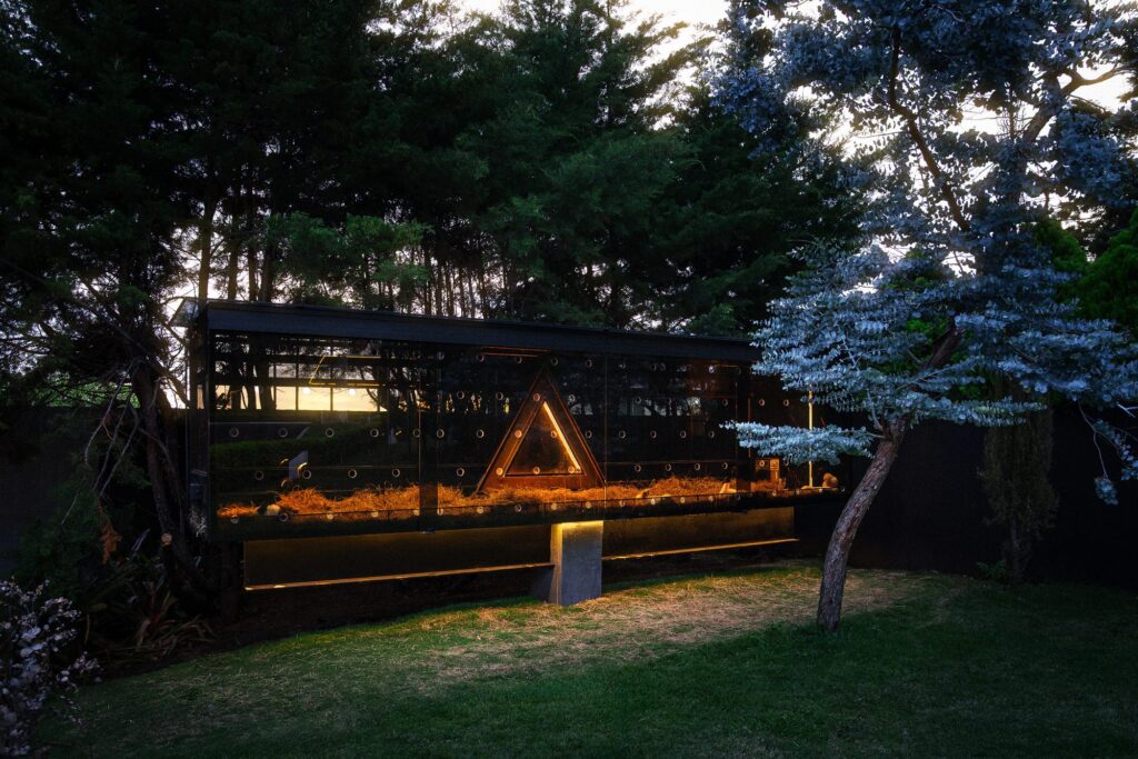 A Nebulae Module at night, warm interior light and a fire pit set against the Costa Rican highlands