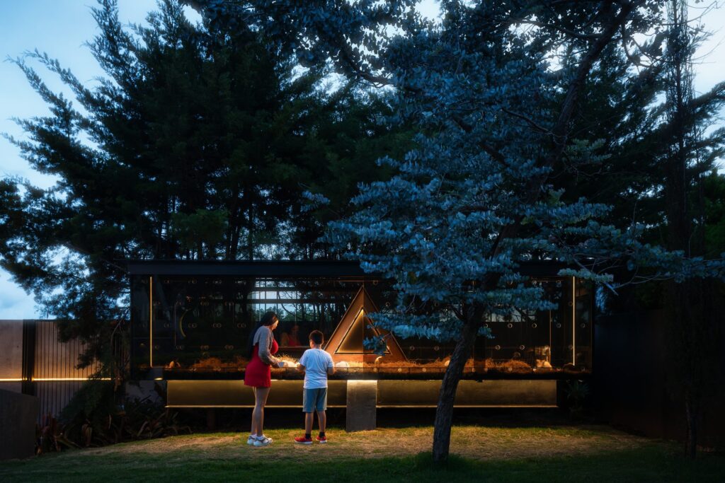 A Module at Nebulae glowing at dusk, guests gathered by the fire amid the mountains of Heredia, Costa Rica