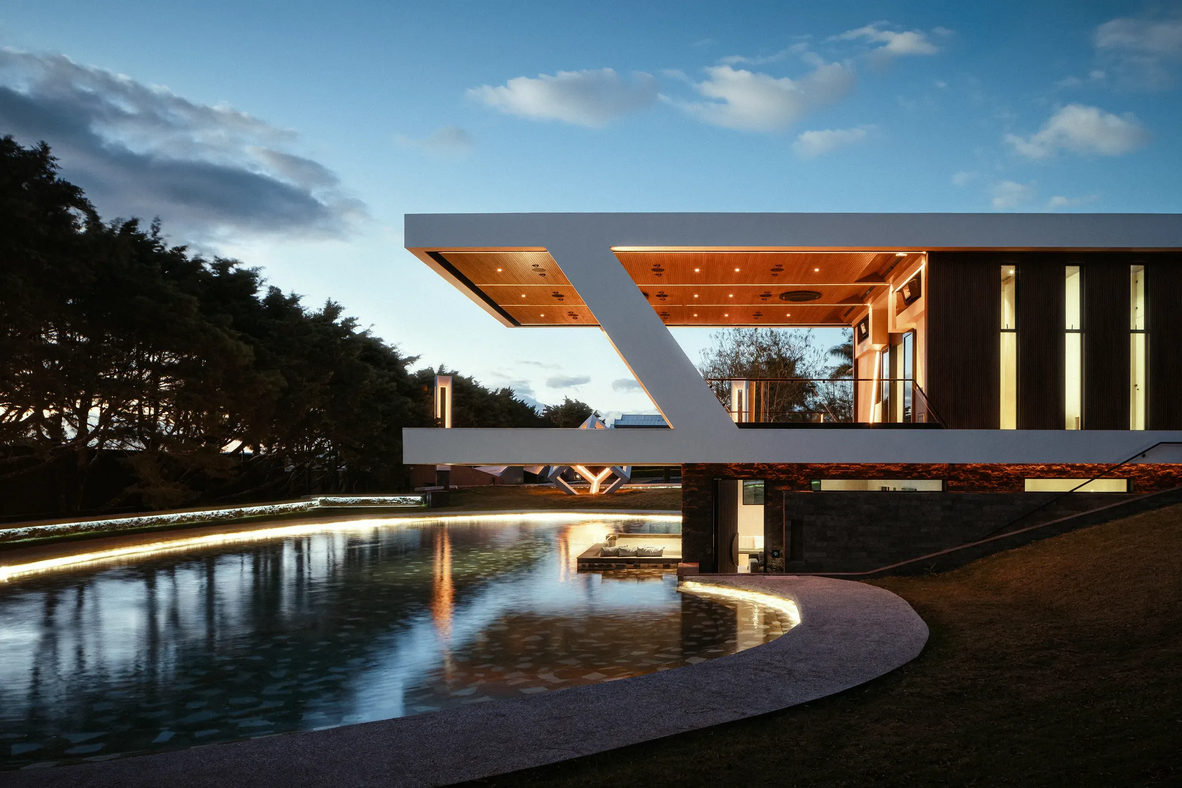 The cantilevered Nebulae pavilion beside the pool under a clear daytime sky