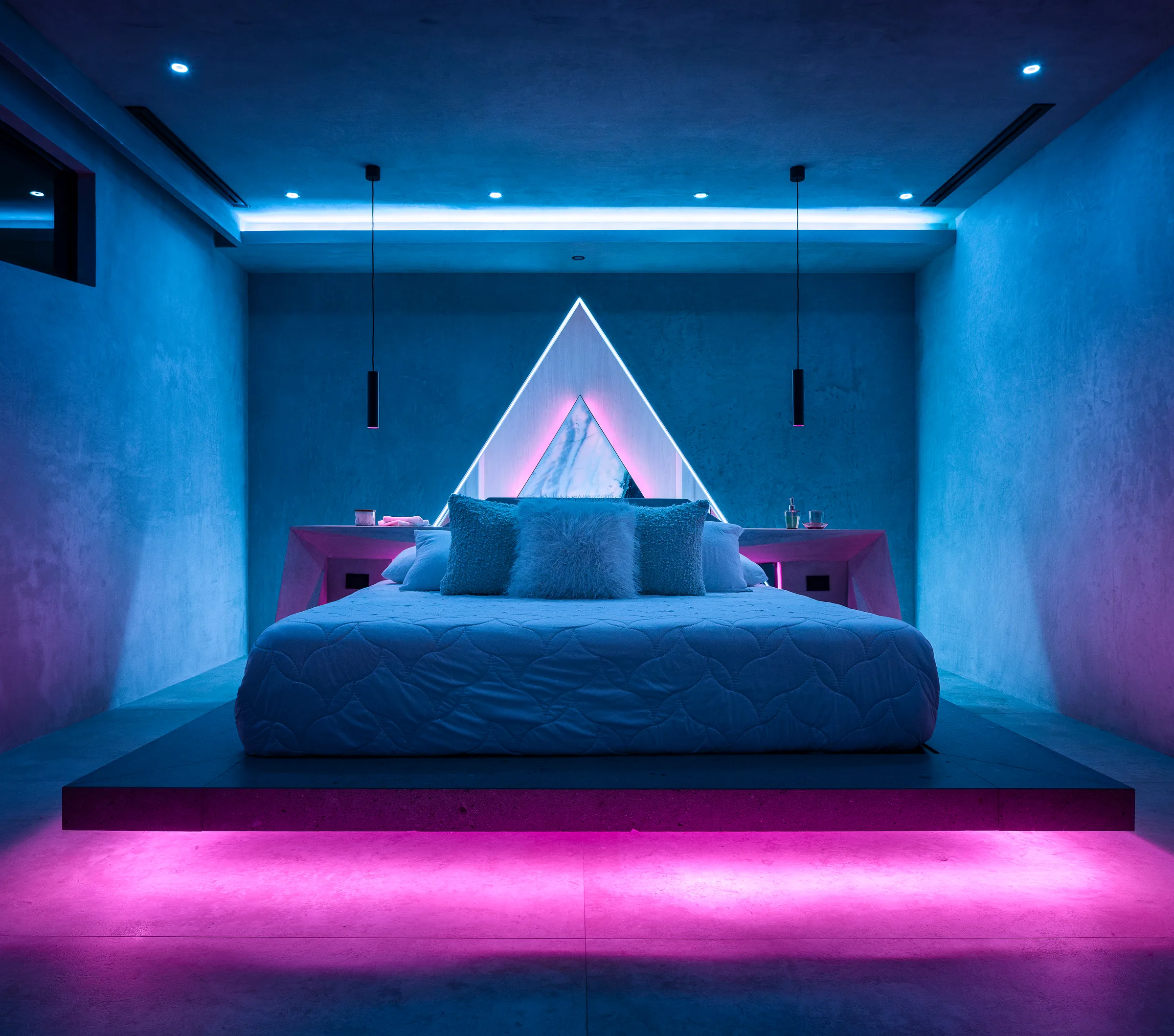 Water Cube bedroom at night bathed in magenta architectural lighting with an illuminated triangular headboard