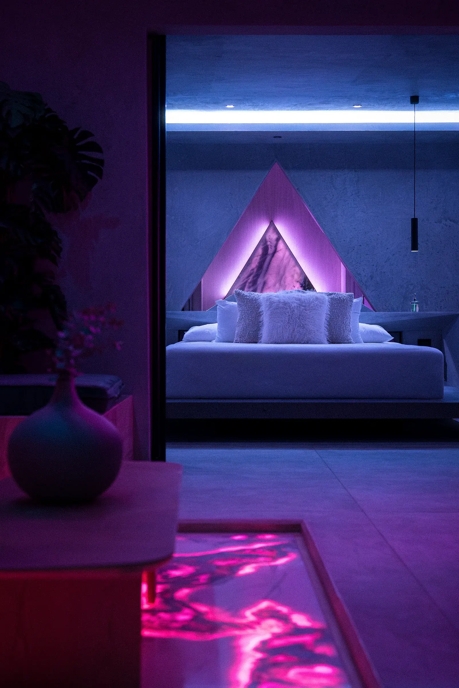 Water Cube living space at night with magenta lighting, a sofa and an illuminated triangular feature