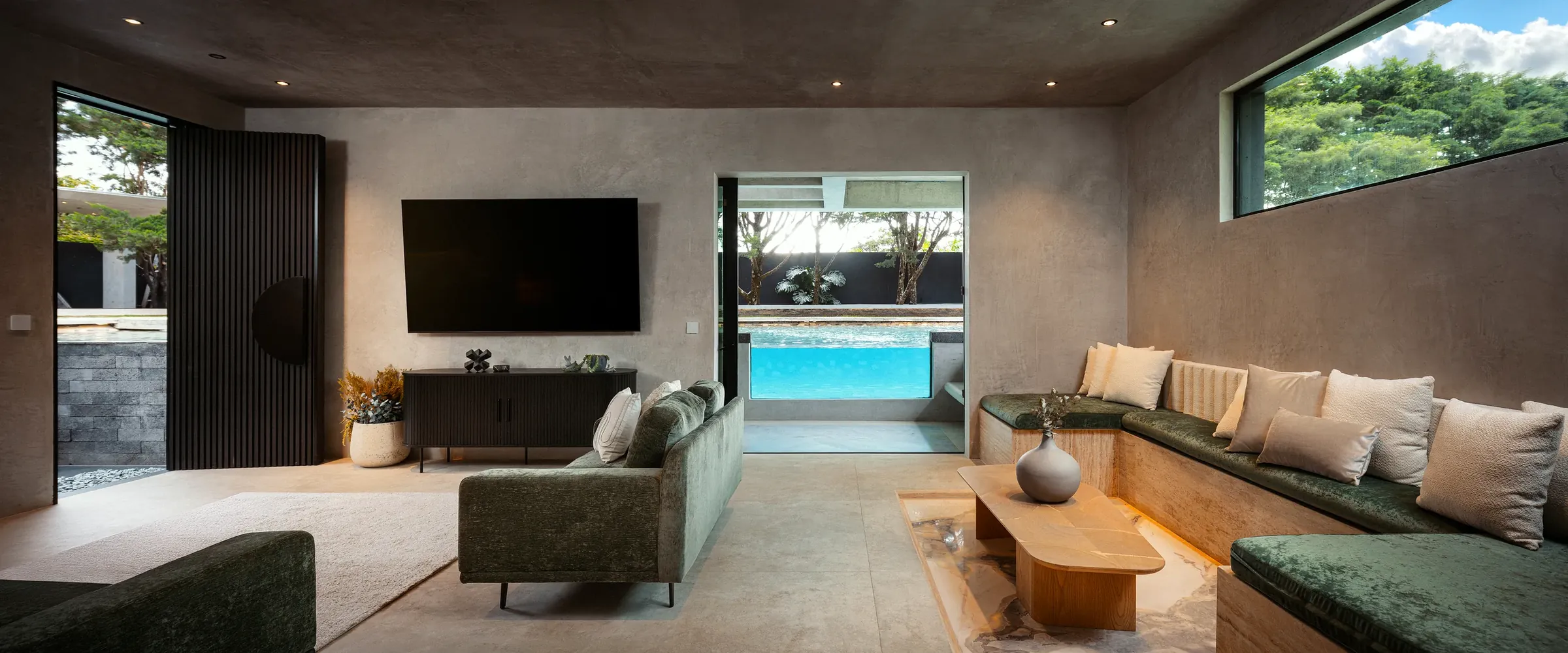 Open-plan living room of the Water Cube Suite with sofa and media wall