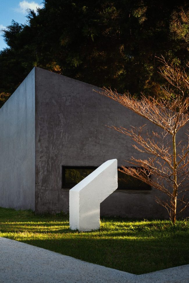 A single concrete Module at Nebulae — pure architectural geometry framed by a tree at golden hour