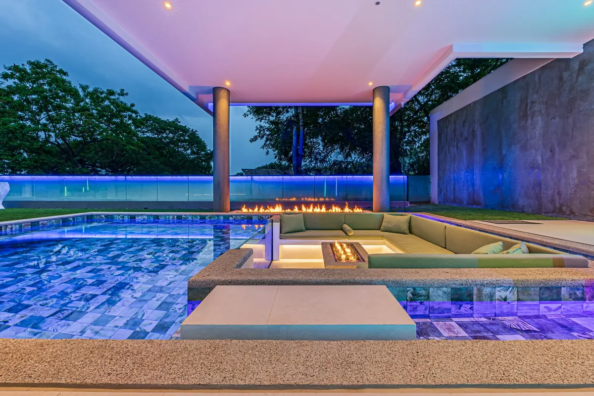 Contemporary Alianz home with illuminated pool and colored accent lighting at dusk