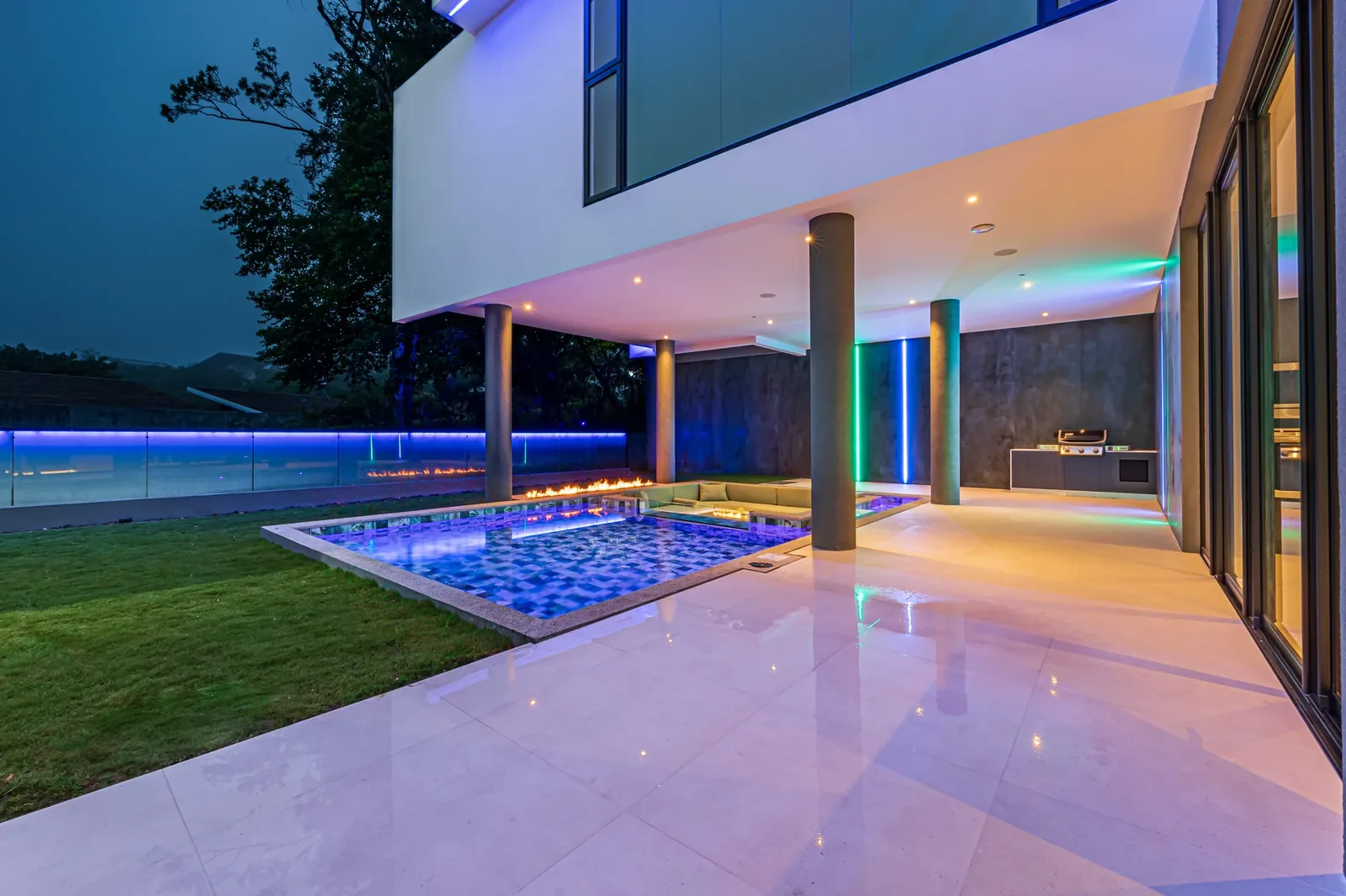 Modern white Alianz house at dusk with cantilevered volume, LED accent lighting and an illuminated pool
