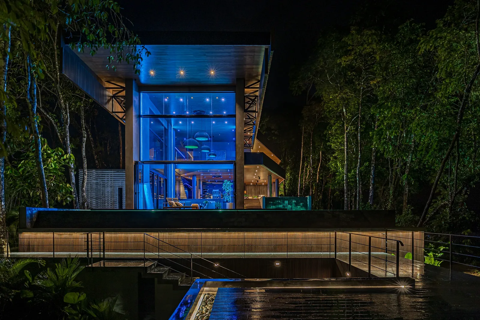 Night view of an Alianz residence and pool carved into the rainforest, every layer of lighting deliberately composed