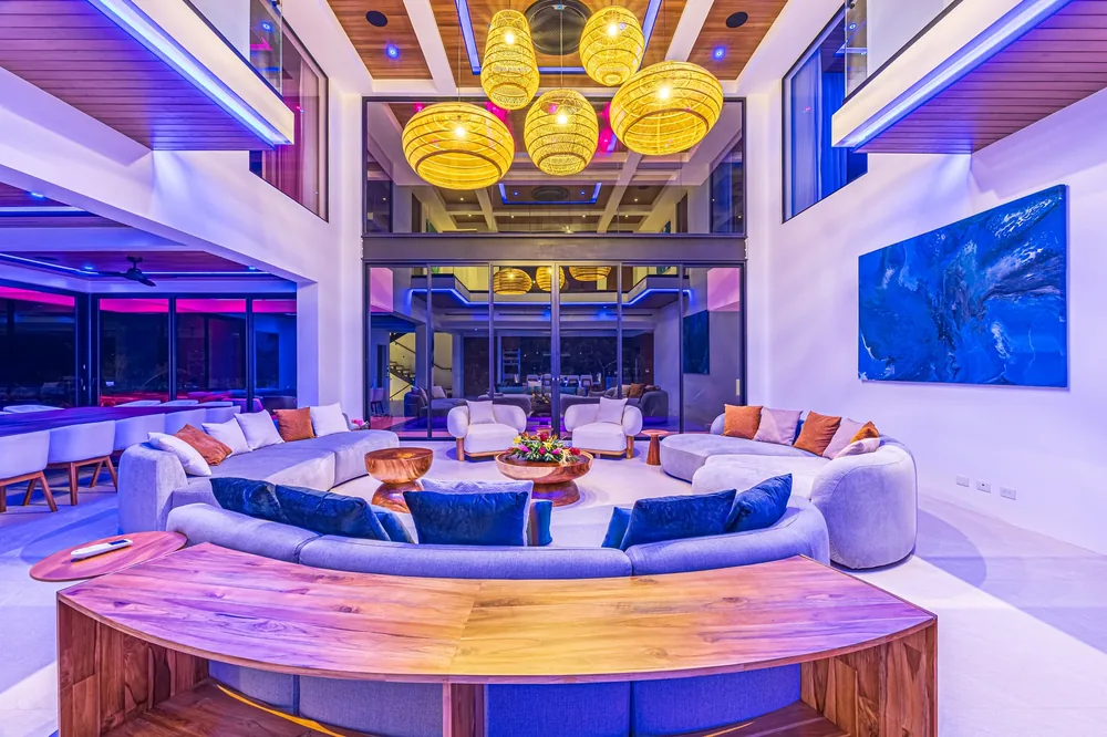 Warmly lit double-height living room prepared for an evening gathering, with sculptural pendant lights