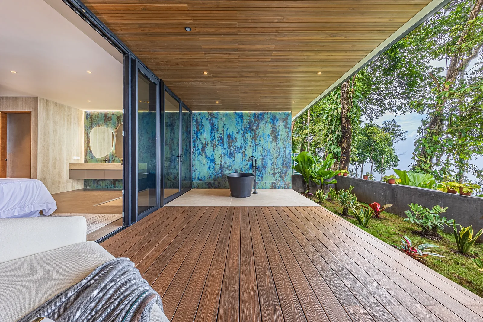 Serene Alianz bedroom opening onto a wooden deck framed by tropical vegetation, in soft natural daylight