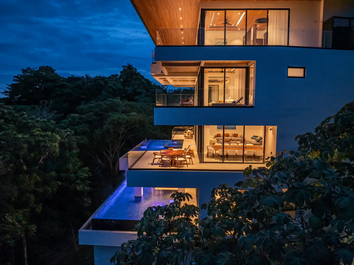Warmly lit Alianz villa seen across the pool terrace at dusk