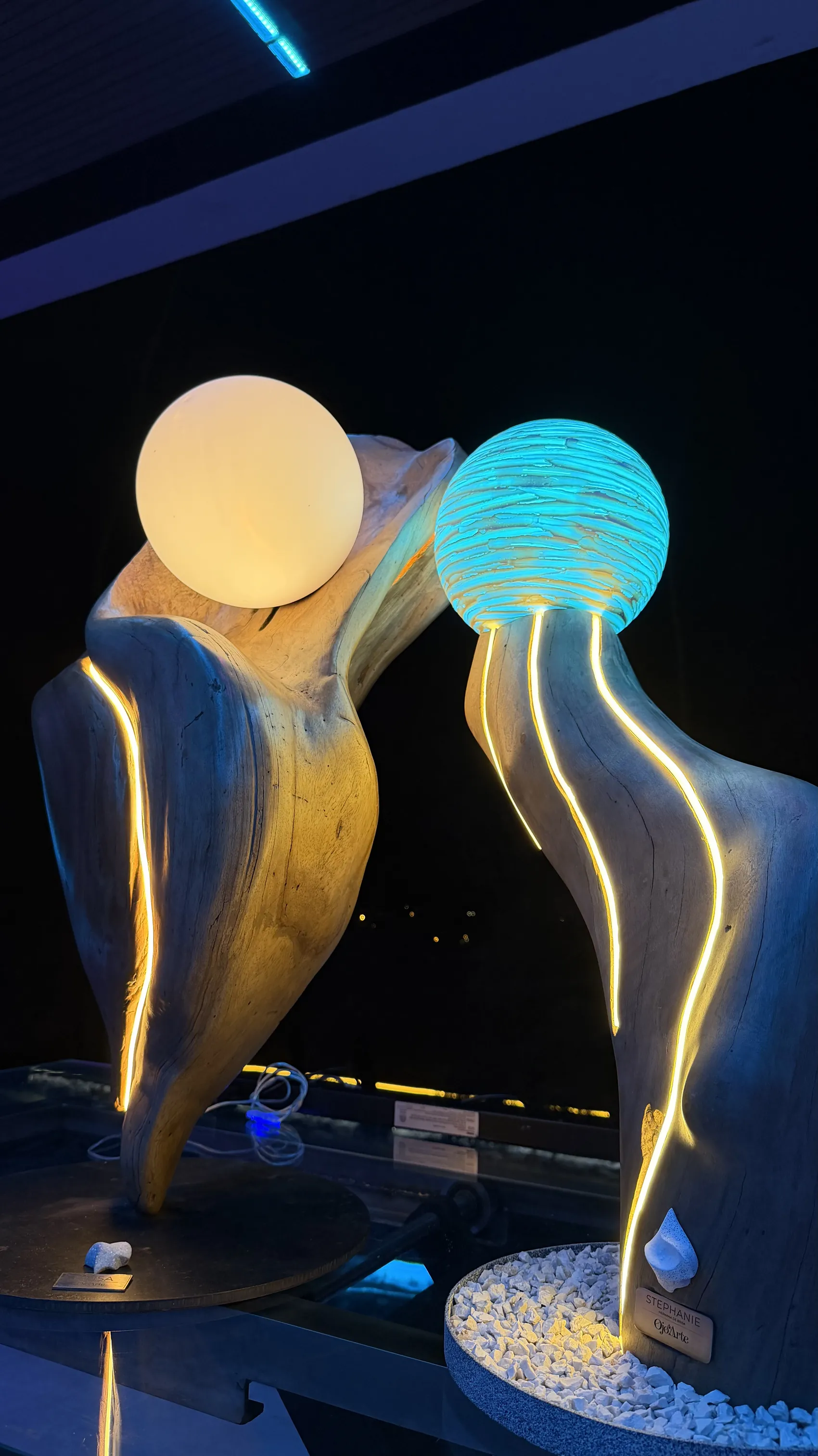 Brisa at night beside a sister sculpture, both crowned by glowing spheres