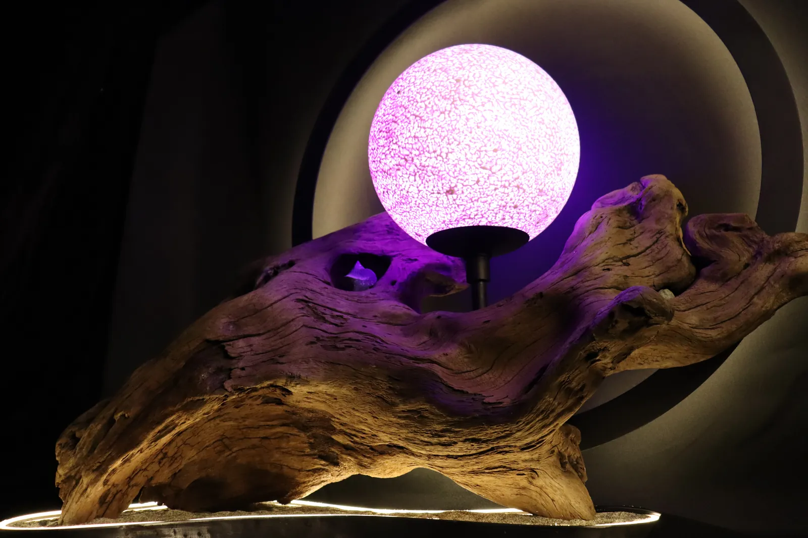 Halo's driftwood body holding the glowing moon, ring rising behind